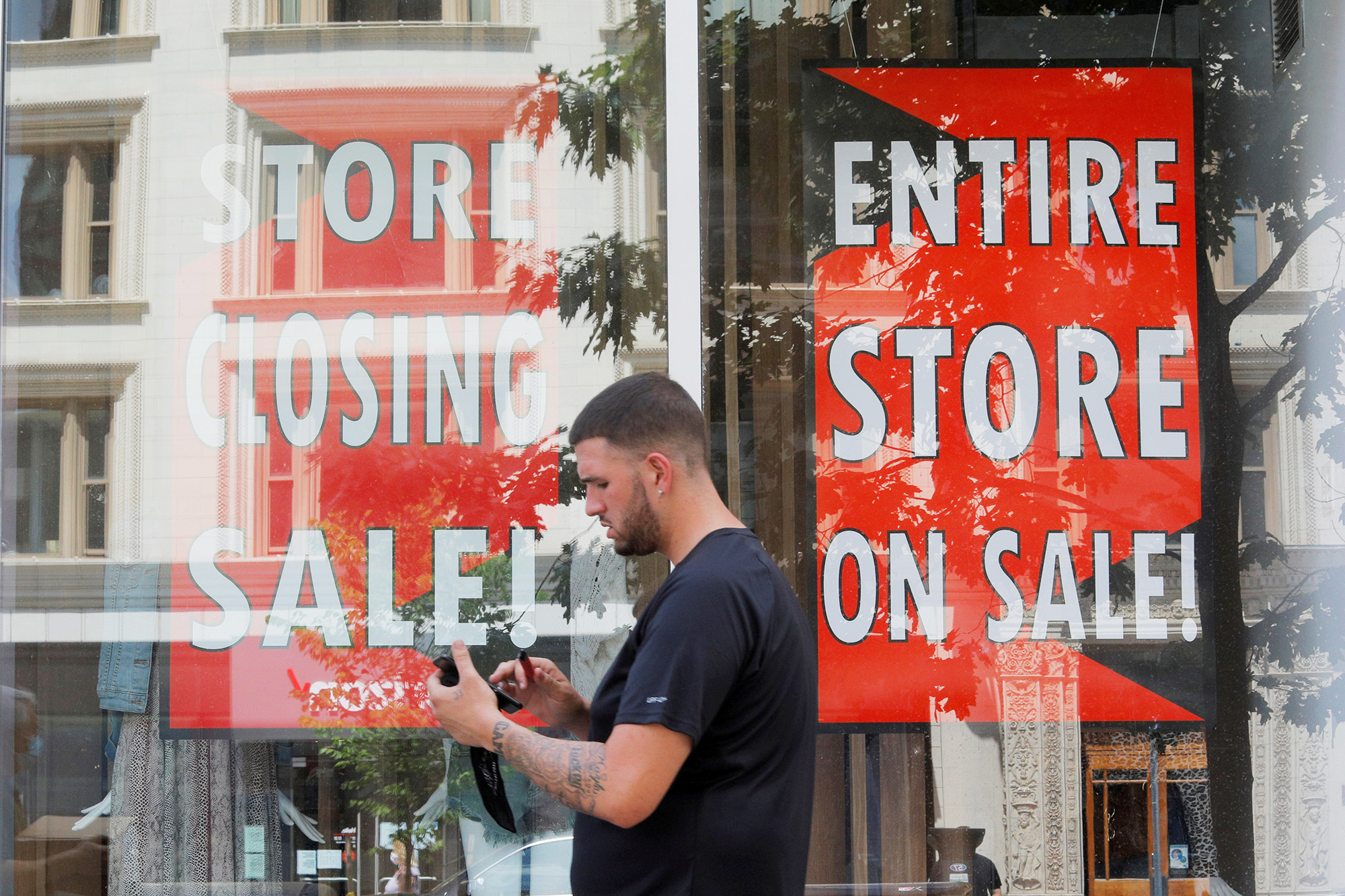 PHOTO: A man walks past signs in the windows of Lord & Taylor, advertising a store closing sale, in Boston, Aug.5, 2020.