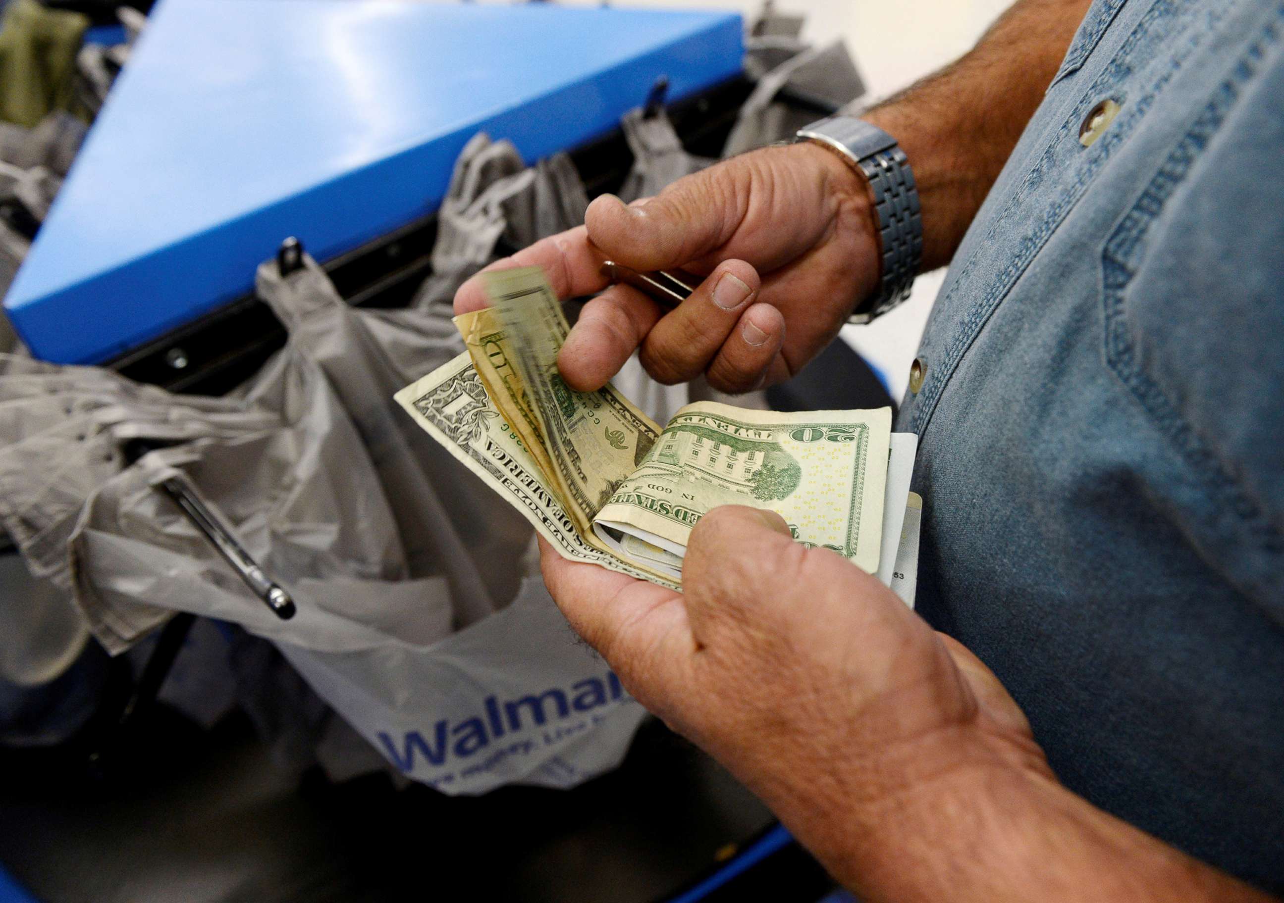 PHOTO: A customer counts his cash at the checkout lane of a Walmart store in the Porter Ranch section of Los Angeles, Nov. 26, 2013.