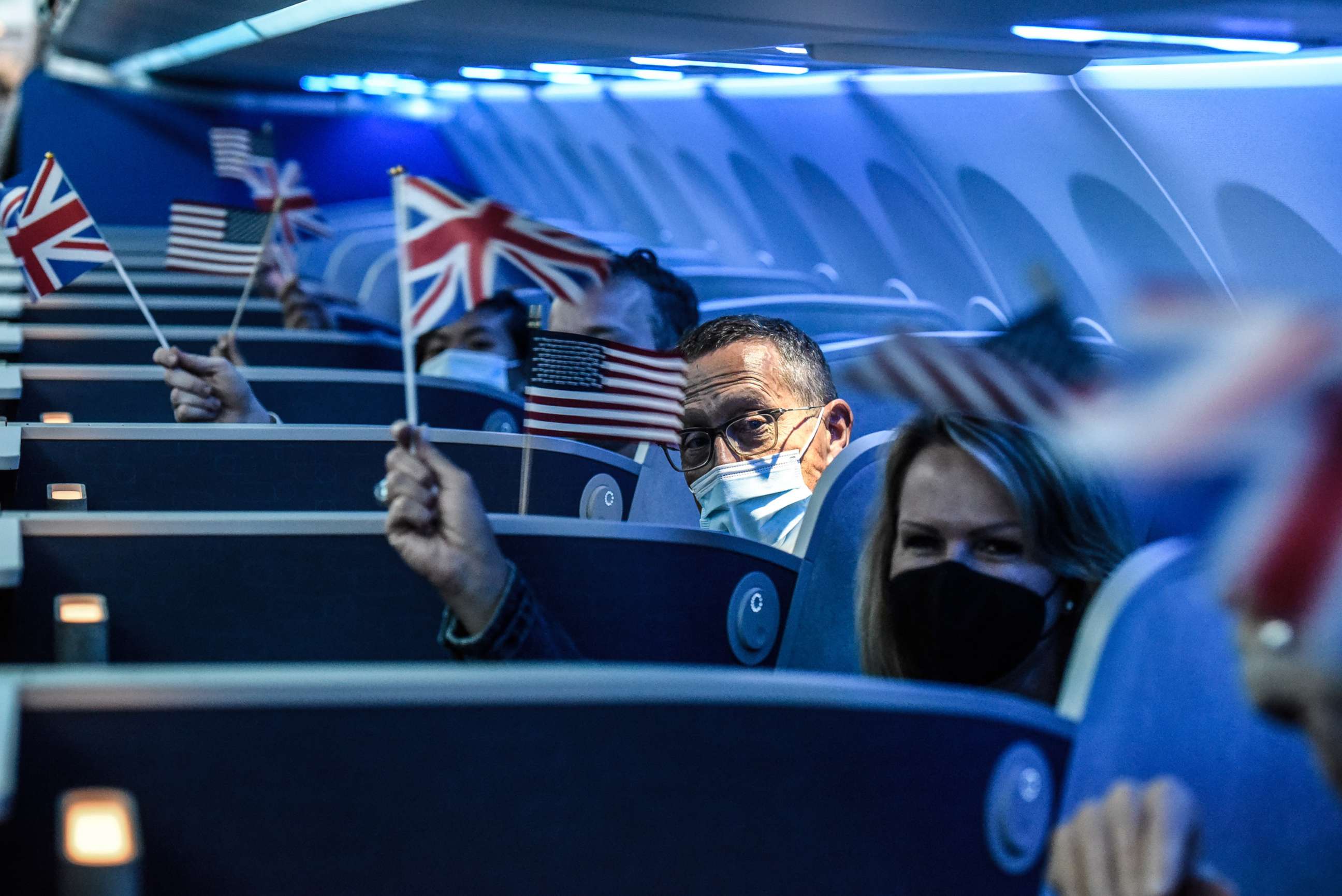 PHOTO: Passengers wave American and the British Union flags on board JetBlue's   inaugural flight to London Heathrow Airport at John F. Kennedy Airport in the   New York, Aug. 11, 2021.