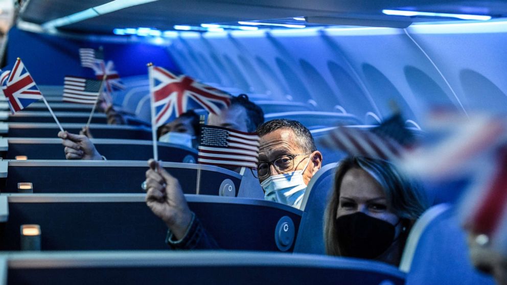 PHOTO: Passengers wave American and the British Union flags on board JetBlue's   inaugural flight to London Heathrow Airport at John F. Kennedy Airport in the   New York, Aug. 11, 2021.