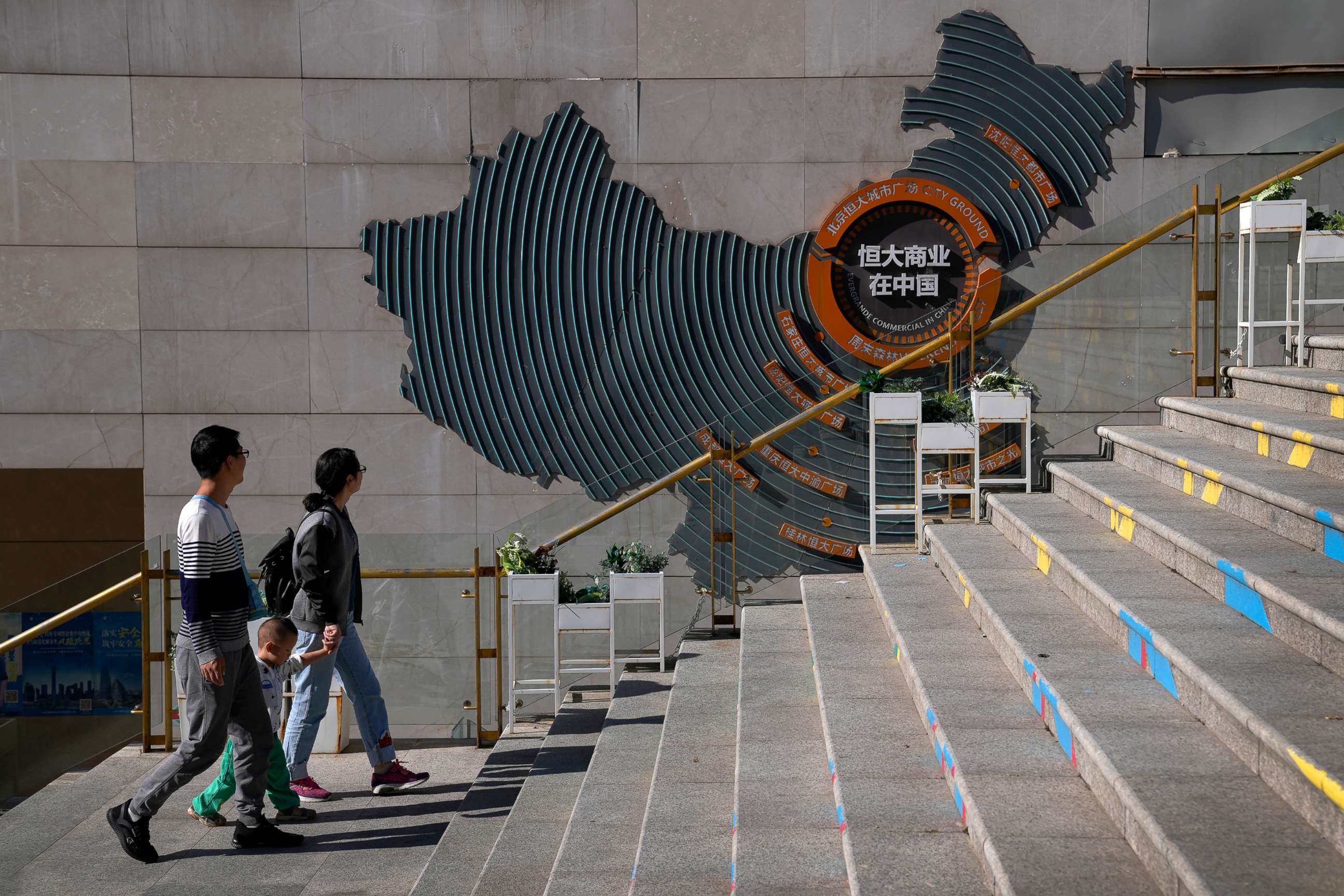 PHOTO: A family walks by a map showing Evergrande development projects in China at an Evergrande city plaza in Beijing, Sept. 21, 2021.