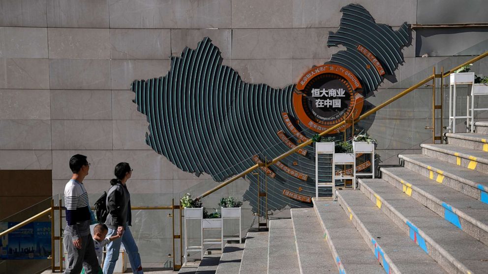 PHOTO: A family walks by a map showing Evergrande development projects in China at an Evergrande city plaza in Beijing, Sept. 21, 2021.