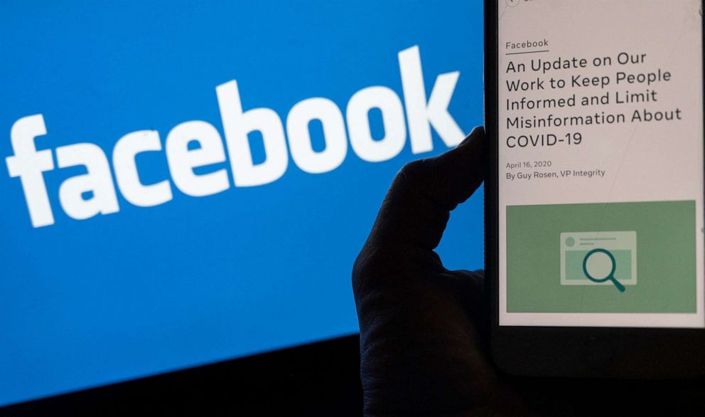PHOTO: In this file photo illustration taken on May 27, 2021, a smart phone screen displays a new policy on COVID-19 misinformation with a Facebook website in the background in Arlington, Va.