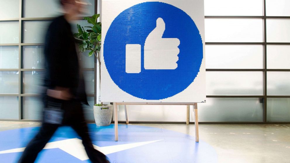 PHOTO: A Facebook employee walks by a sign displaying the "like" sign at Facebook's corporate headquarters campus in Menlo Park, Calif., Oct. 23, 2019.