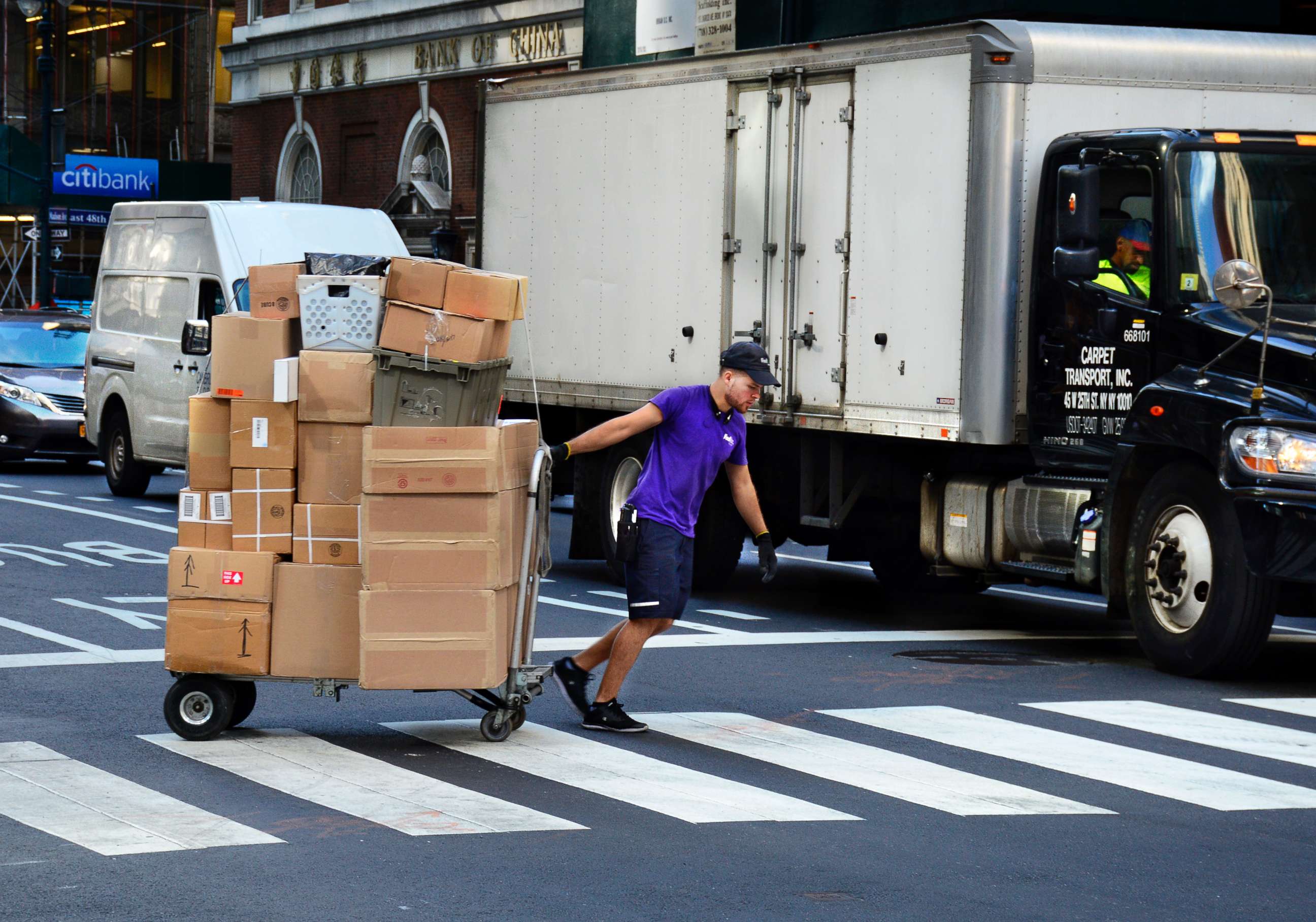 PHOTO: A Federal Express deliveryman pulls a cart loaded with packages across a street in New York.