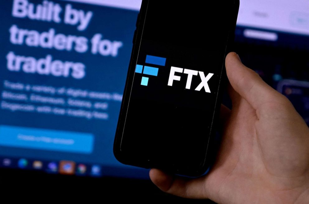PHOTO: In this Feb. 10, 2022, file photo, a smart phone screen is displaying the logo of FTX, the crypto exchange platform, with a screen showing the FTX website in the background.