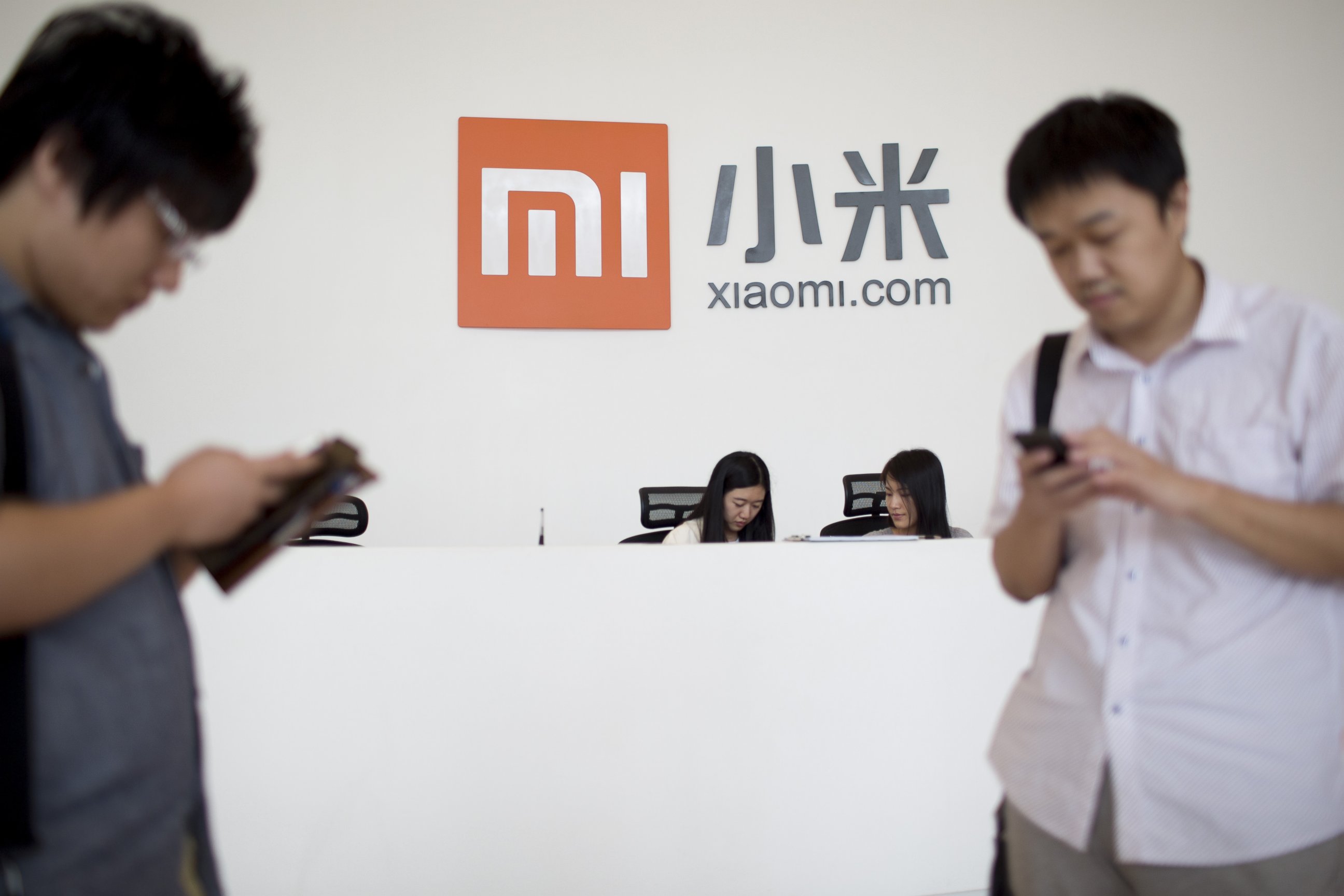 PHOTO: Visitors use mobile phones in front of a reception desk at the Xiaomi Corp. headquarters in Beijing, China, Sept. 12, 2014. 