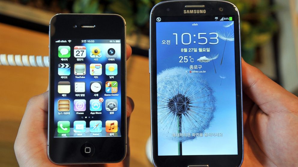 An employee shows an Apple's iPhone 4s (L) and a Samsung's Galaxy S3 (R) at a mobile phone shop in Seoul on August 27, 2012. 