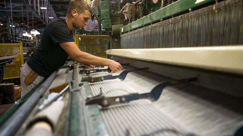 An employee adjusts an industrial-sized loom as it creates a roll of carpet at the Bloomsburg Carpet Industries Inc. manufacturing facility in Bloomsburg, Pennsylvania, Aug. 29, 2013.