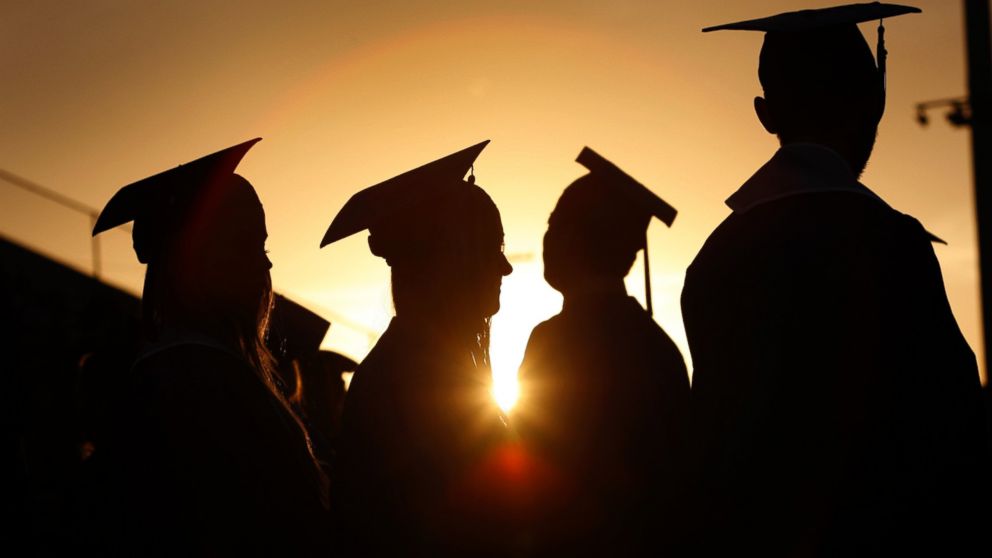 College graduates are silhouetted at sunset as they line up to receive their diplomas during a graduation ceremony in Santa Monica, Calif., June 11, 2013.