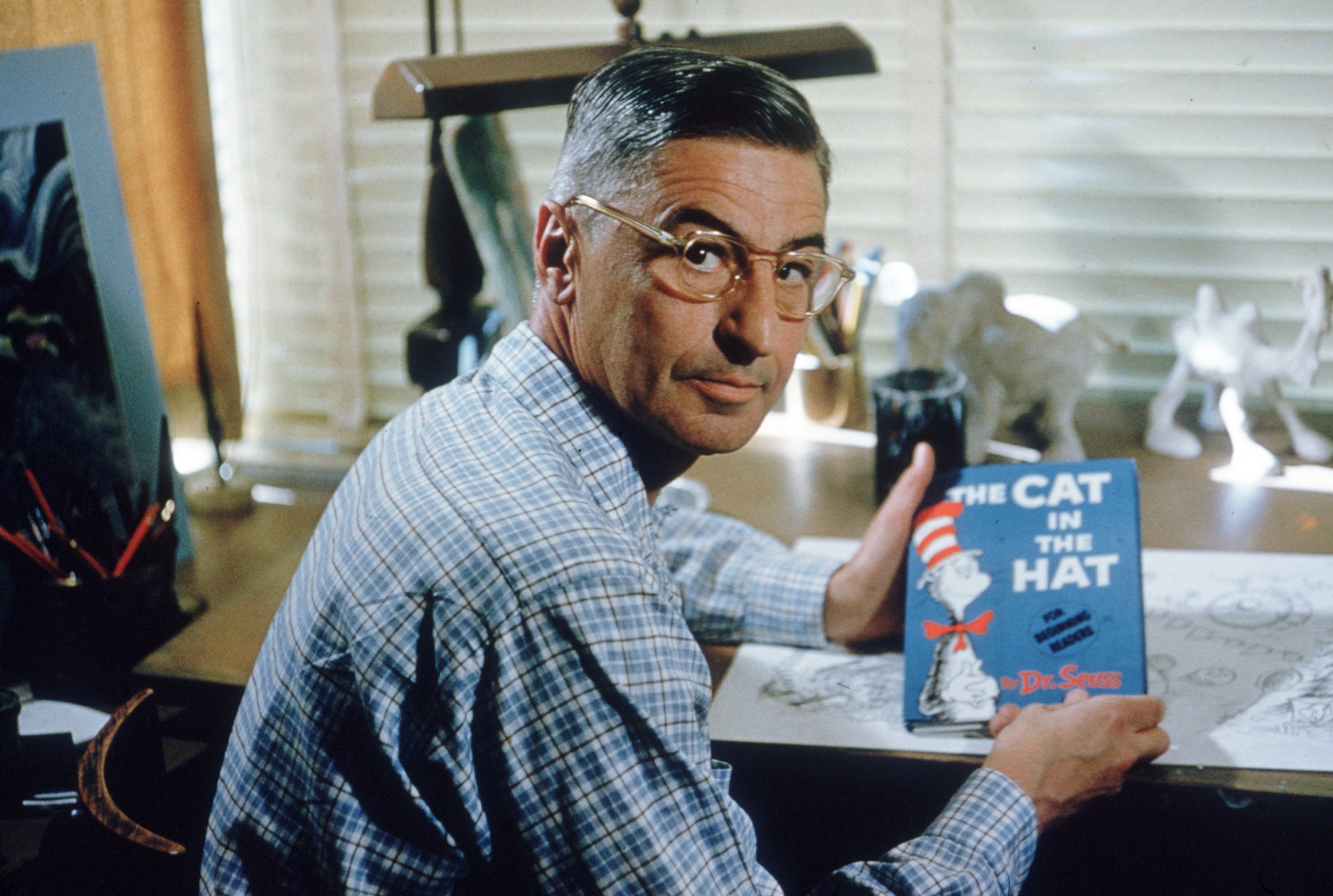 PHOTO: Author and illustrator Theodor Seuss Geisel sits at his drafting table in his home office with a copy of his book, "The Cat in the Hat" in La Jolla, Calif., April 25, 1957.