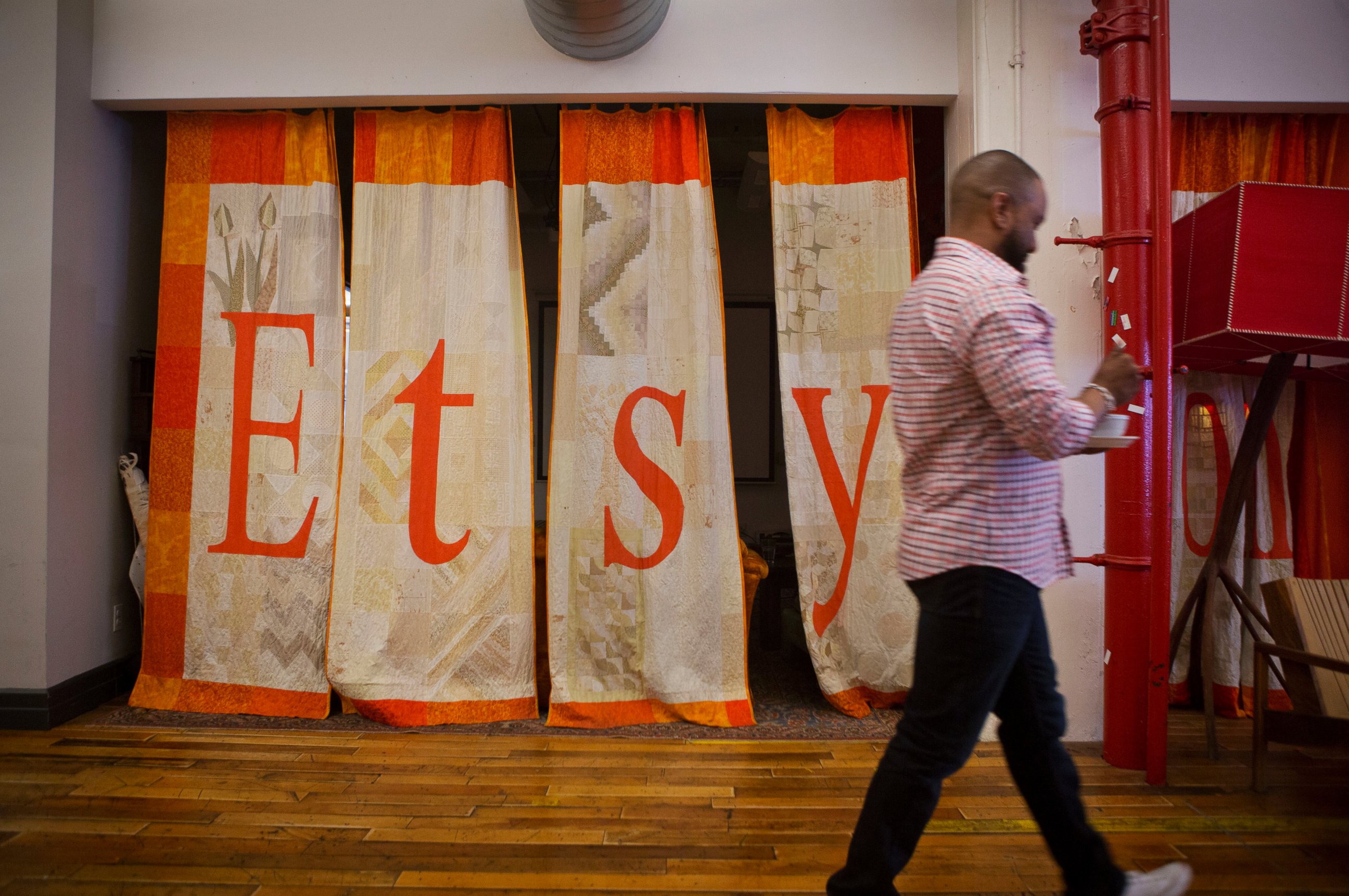 PHOTO: An employee walks past a quilt displaying Etsy Inc. signage at the company's headquarters in the Brooklyn borough of New York, May 4, 2015.