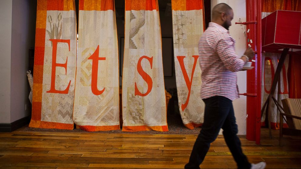 PHOTO: An employee walks past a quilt displaying Etsy Inc. signage at the company's headquarters in the Brooklyn borough of New York, May 4, 2015.