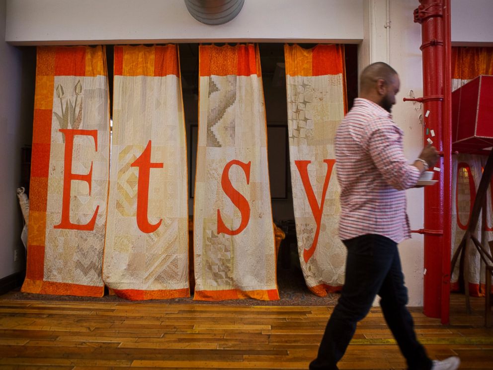 PHOTO: An employee walks past a quilt displaying Etsy Inc. signage at the companys headquarters in the Brooklyn borough of New York, May 4, 2015.