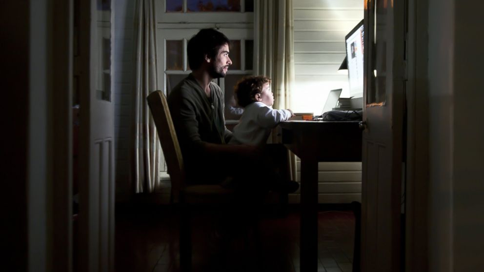 An undated stock image shows a man and a child using a home computer.