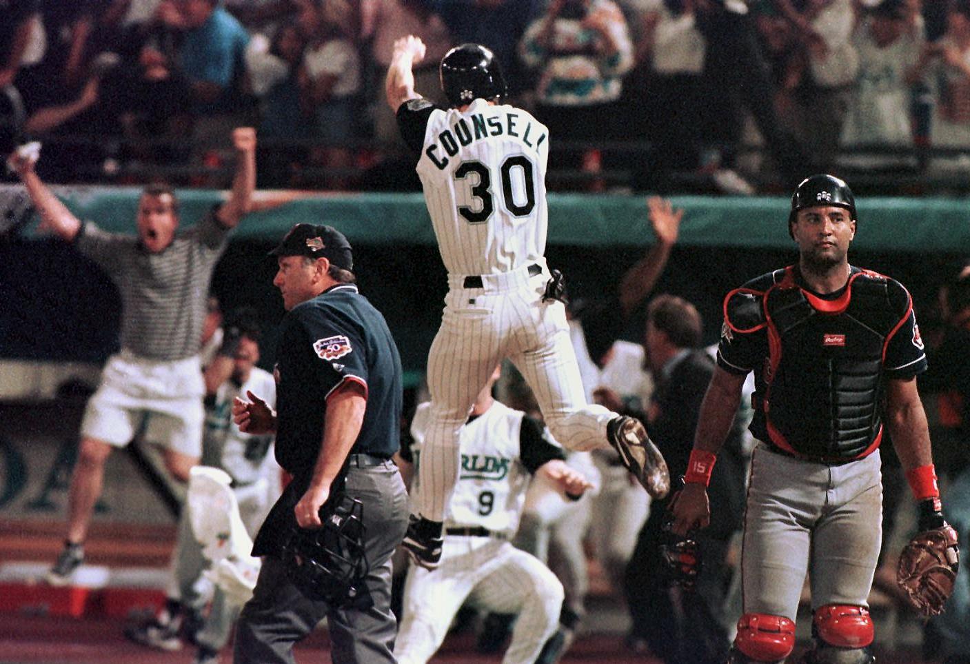 PHOTO: Florida Marlins player Craig Counsell jumps in the air after crossing the plate with the winning run as Cleveland Indians catcher Sandy Alomar walks off the field in game seven of the World Series, Oct. 26 1997, at Pro Player Stadium in Miami.   