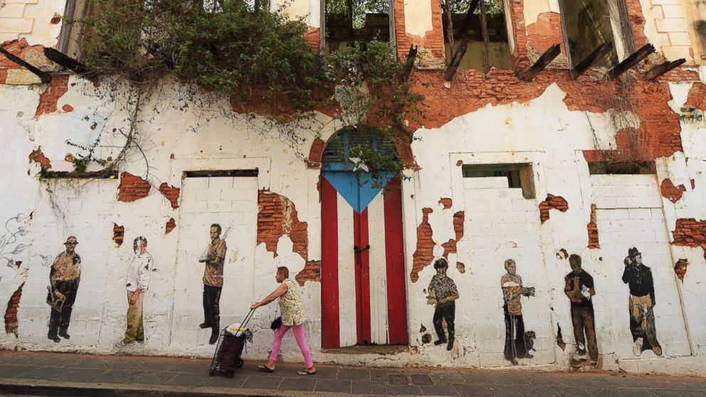 PHOTO: A woman walks by a rundown building on Saturday July 04, 2015 in Old San Juan, Puerto Rico.
