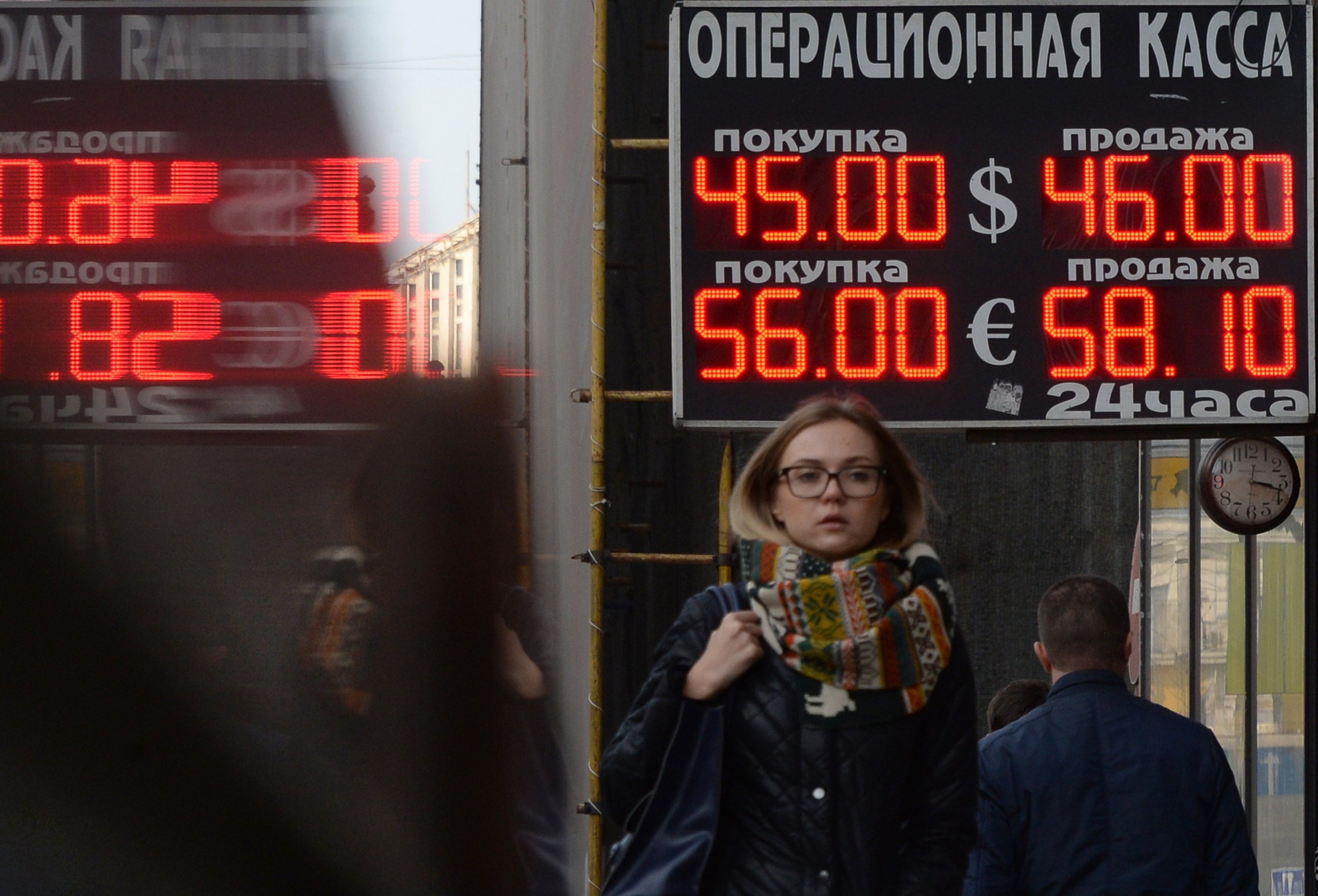 PHOTO: Pedestrians walk under a board listing foreign currency rates against the Russian ruble outside an exchange office in central Moscow, Nov. 10, 2014. R