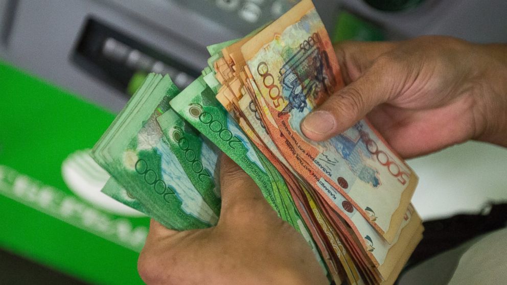 PHOTO: A customer counts tenge currency banknotes inside a bank in Almaty, Kazakhstan, June 23, 2015.