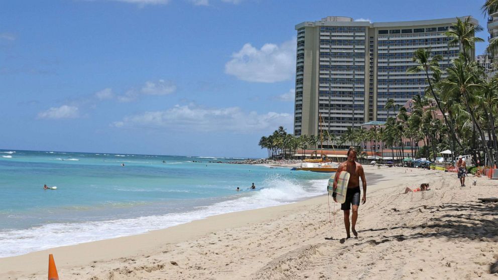 PHOTO: A surfer walks on a sparsely populated Waikiki beach in Honolulu, June 5, 2020.
