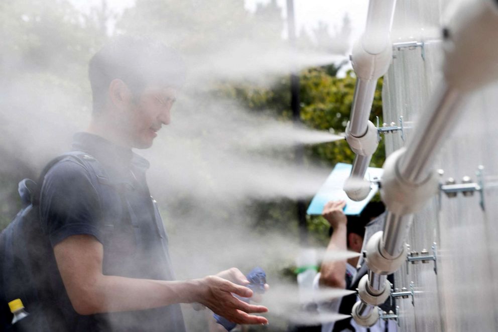 PHOTO: A man cools off at a mist station installed at Shiokaze Park during the beach volleyball test event for the Tokyo 2020 Olympic Games on July 25, 2019 in Tokyo.