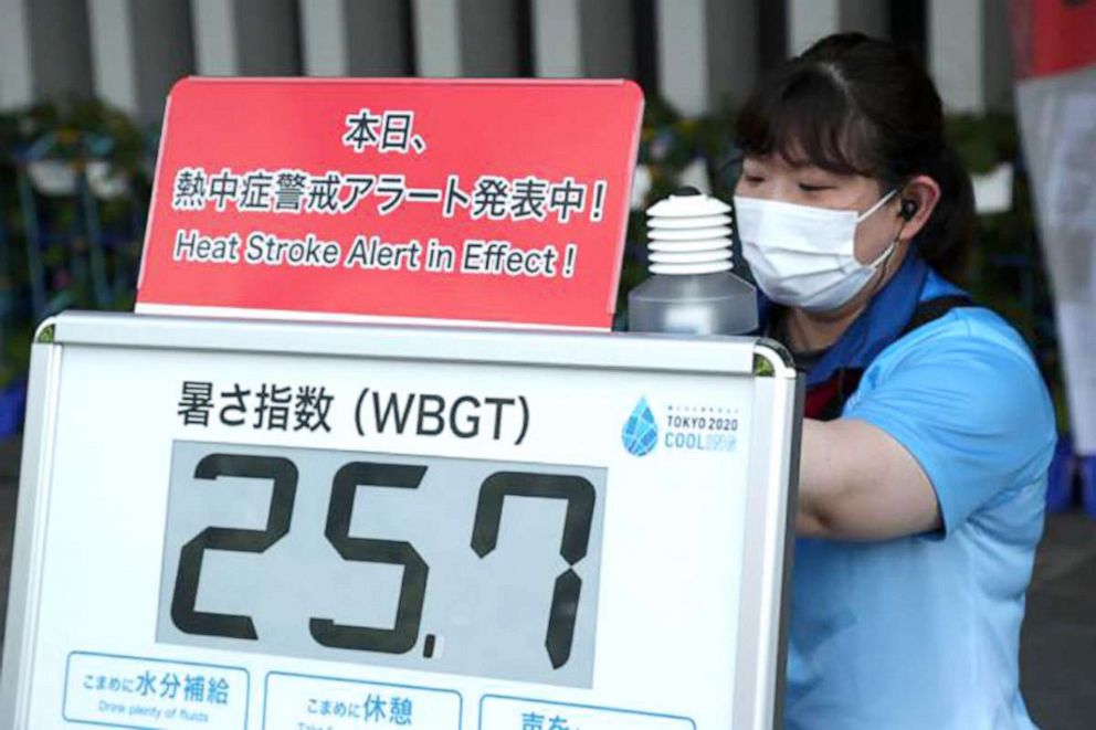 PHOTO: A woman attaches a heat warning sign at the Nippon Budokan martial arts hall on 26 July 2021 in Tokyo.