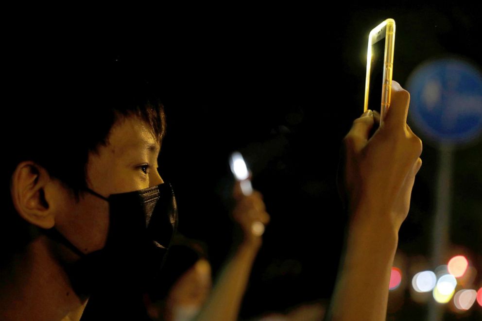 PHOTO: A man holds up his phone as people form a human chain during a protest in Tai Po, Hong Kong, Oct. 11, 2019.