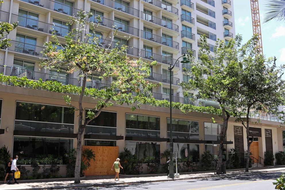 PHOTO: In this photo taken Friday, June 5, 2020, people walk past the closed doors of the Hilton Garden Inn hotel in Honolulu.