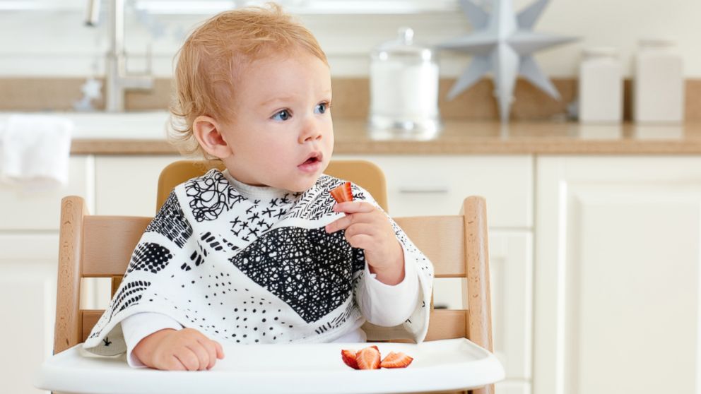 A large burp cloth by baby brand aden + anais serves a dual purpose as a bib with hidden snap buttons. 