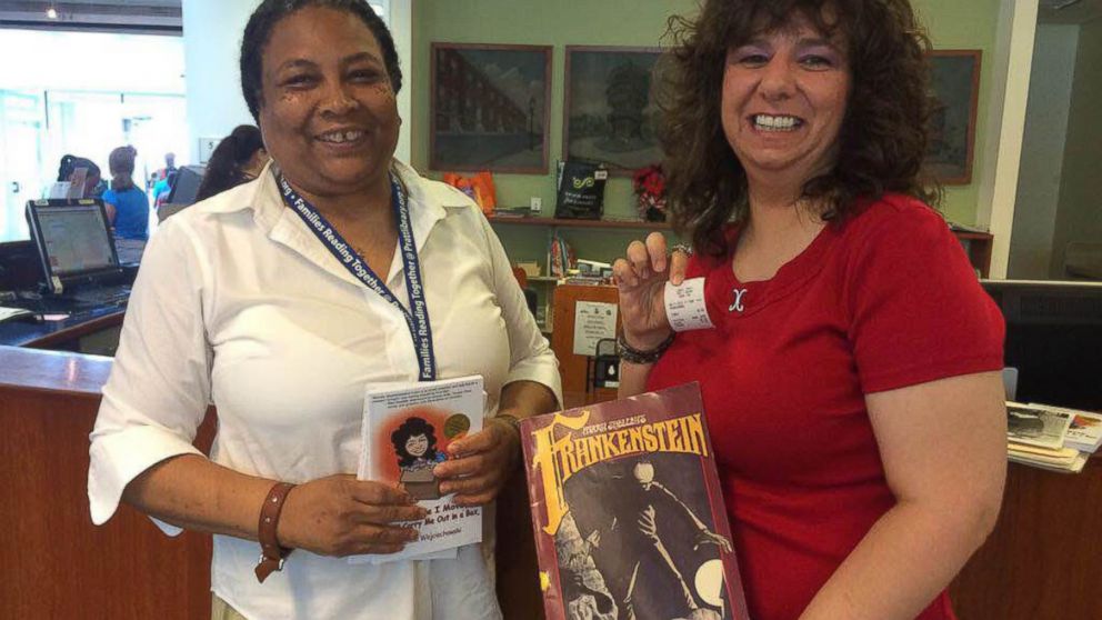 PHOTO: Lynne Distance, Enoch Pratt Free Library Southeast Anchor Library Branch Manager, accepts the overdue book from Michele Wojciechowski, right, June 11, 2015, in Baltimore, Maryland.