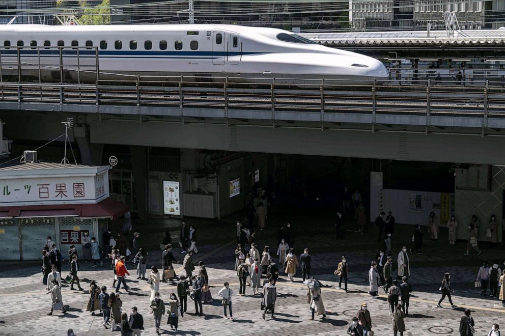 PHOTO: People walk near Yurakucho station while a Shinkansen, or high speed bullet train, arrives in Tokyo, April 10, 2021.