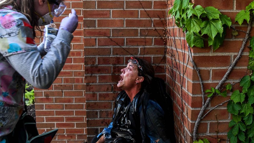 PHOTO: A medic protestor assists a member of the media after police started firing tear gas and rubber bullets near the 5th police precinct during a demonstration on May 30, 2020, in Minneapolis.