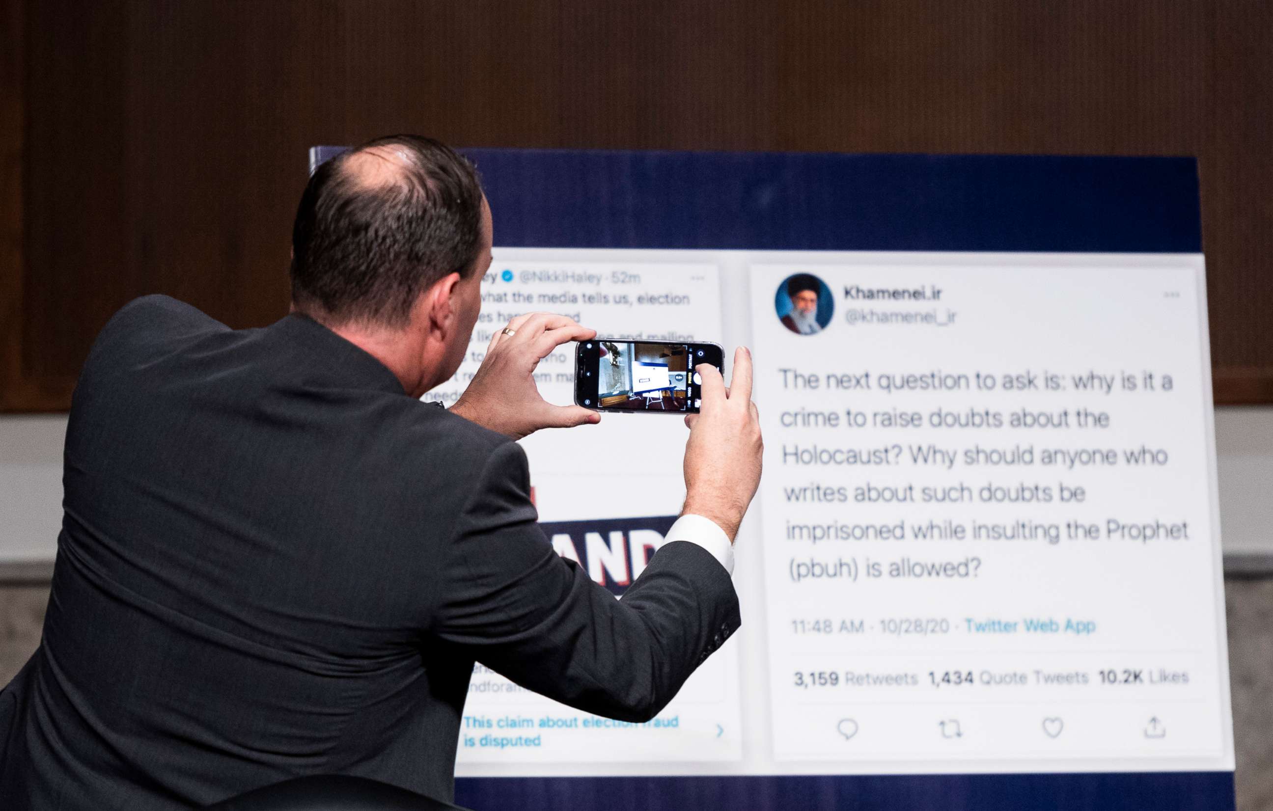 PHOTO: Sen. Mike Lee takes a photo of a poster featuring tweets from Nikki Haley and Sayyid Ali Khamenei at the Senate Judiciary Committee hearing on "Breaking the News: Censorship, Suppression, and the 2020 Election," Nov. 17, 2020 in Washington, D.C.