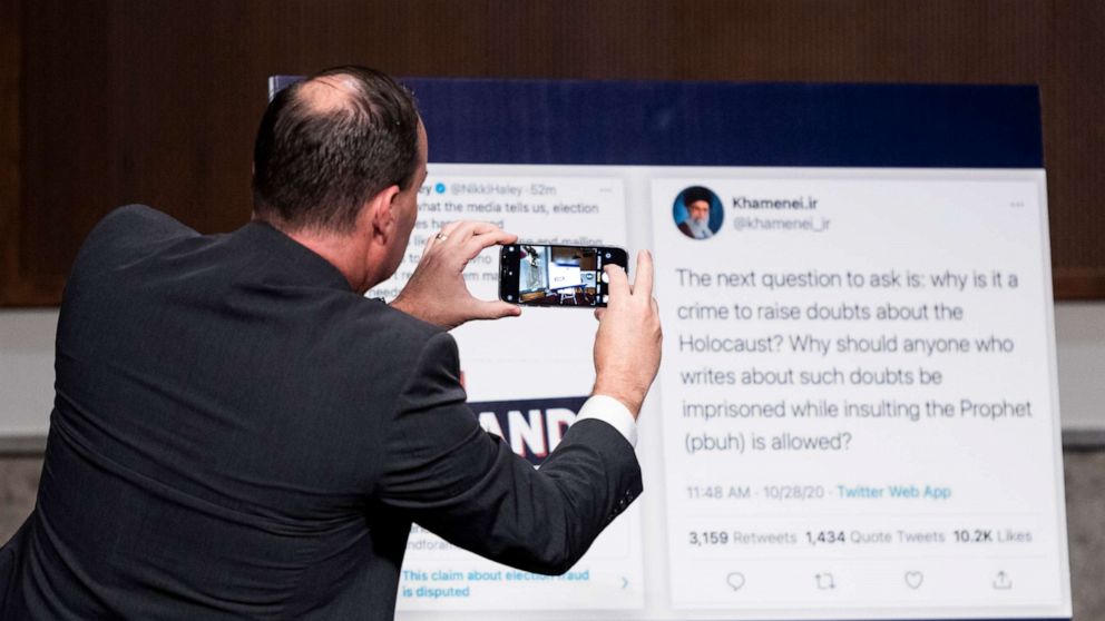 PHOTO: Sen. Mike Lee takes a photo of a poster featuring tweets from Nikki Haley and Sayyid Ali Khamenei at the Senate Judiciary Committee hearing on "Breaking the News: Censorship, Suppression, and the 2020 Election," Nov. 17, 2020 in Washington, D.C.