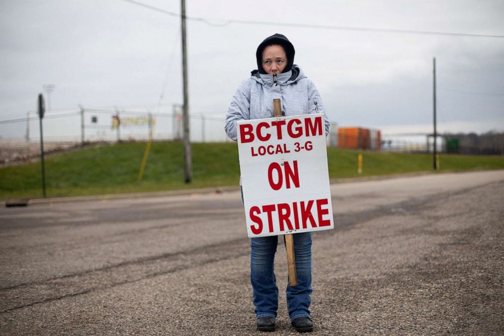 PHOTO: Megan Cole, a 13-year employee, tries to stay warm as she holds while picketing outside of the Kellogg's Porter Street plant in Battle Creek, Mich., Dec. 11, 2021.