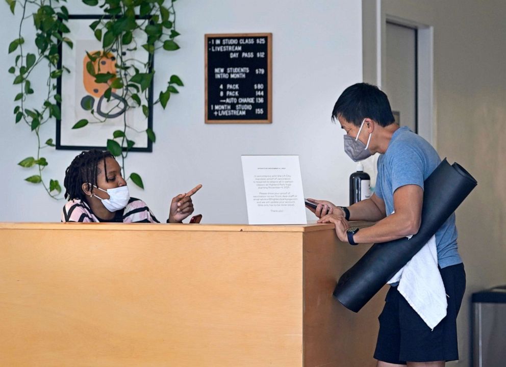 PHOTO: Erica Adamson, left, verifies a mobile digital COVID-19 Vaccine Record on Tony Lai's iPhone at the Highland Park Yoga in Los Angeles, Nov. 6, 2021.