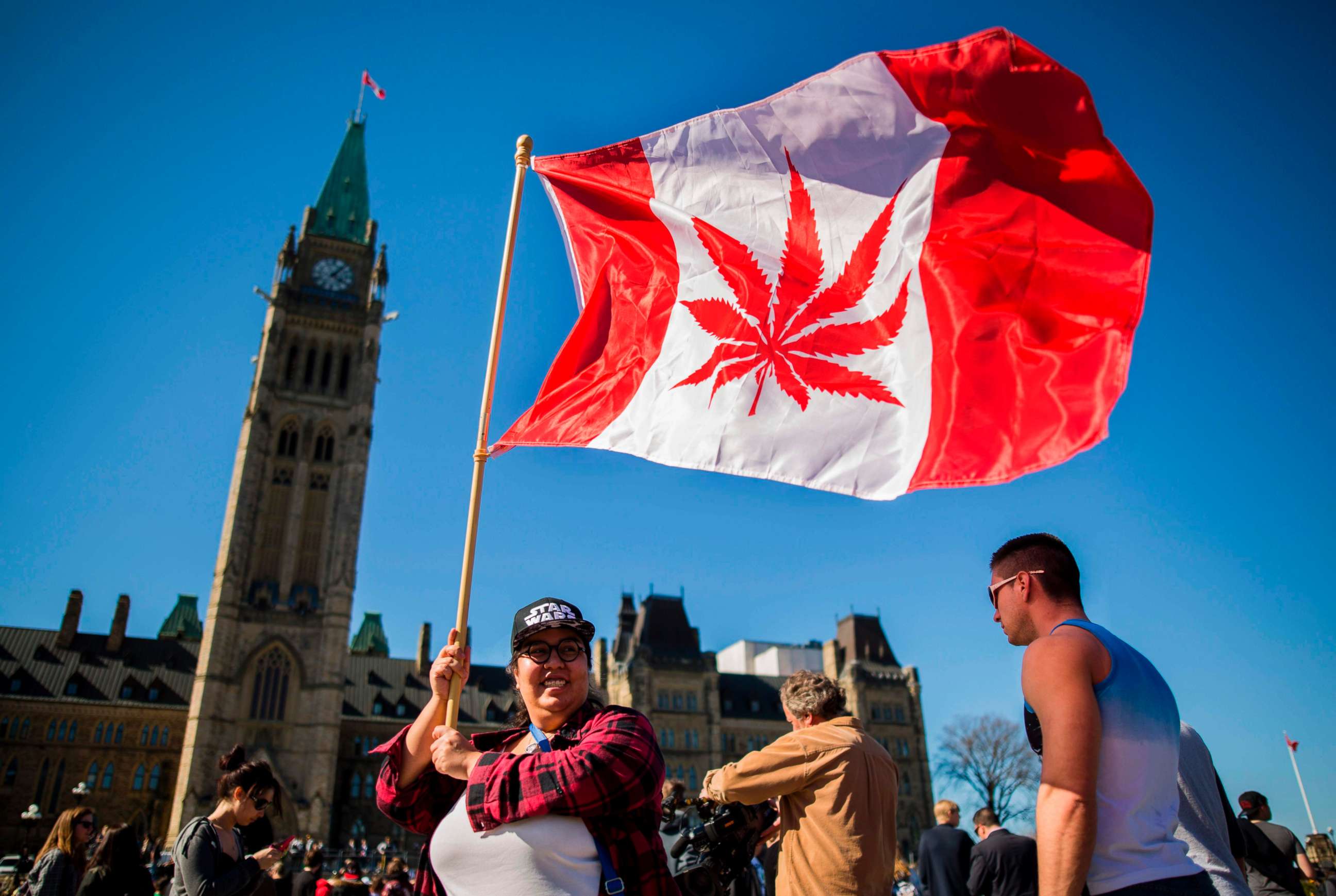 PHOTO: A woman waves a flag with a marijuana leaf on it next to a group gathered to celebrate National Marijuana Day on Parliament Hill in Ottawa, Canada, April 20, 2016. 
