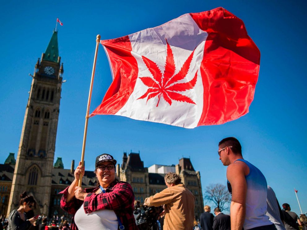 PHOTO: A woman waves a flag with a marijuana leaf on it next to a group gathered to celebrate National Marijuana Day on Parliament Hill in Ottawa, Canada, April 20, 2016.