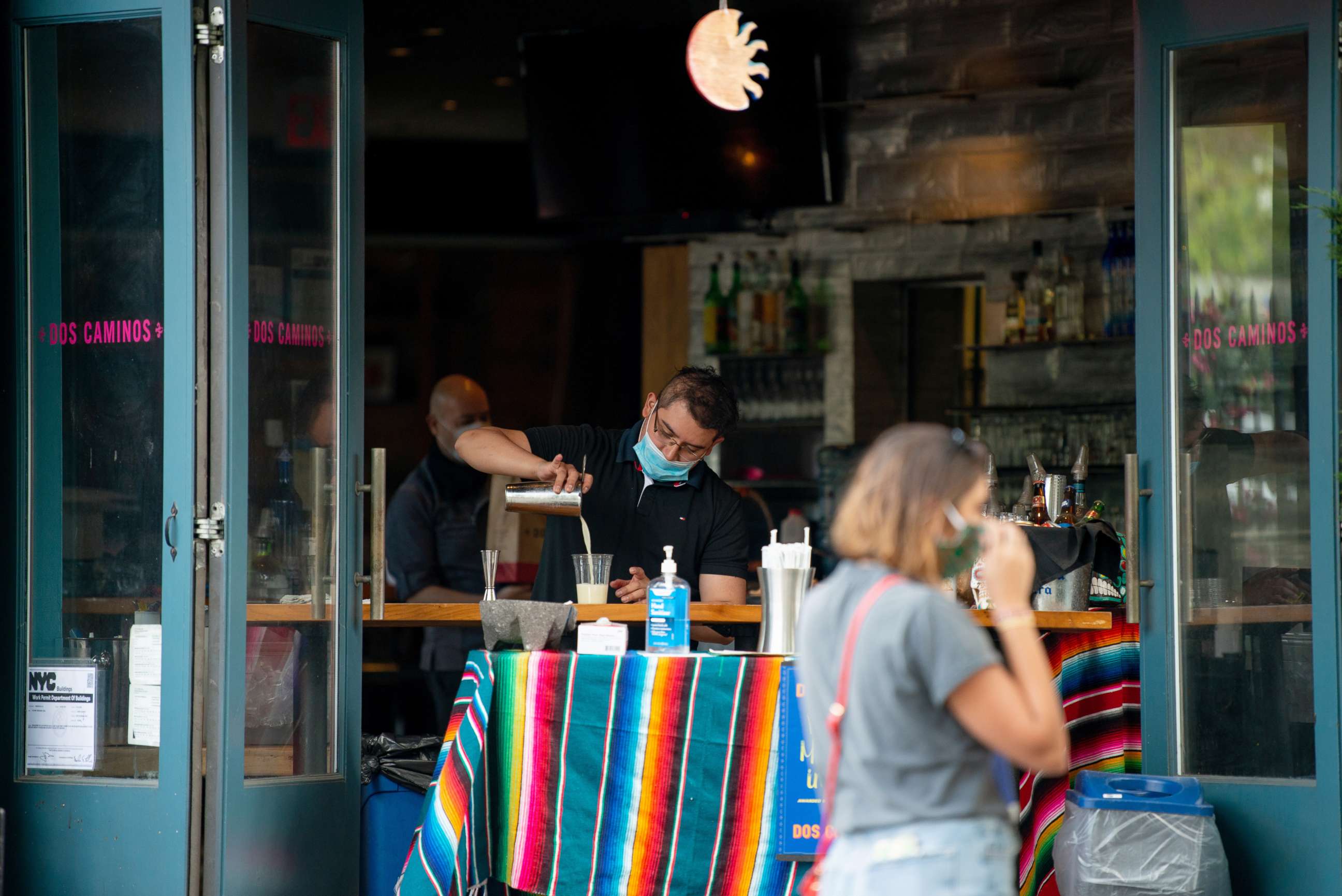 PHOTO: A restaurant employee wearing a mask pours an alcoholic drink into a plastic cup on May 31, 2020 in New York City.