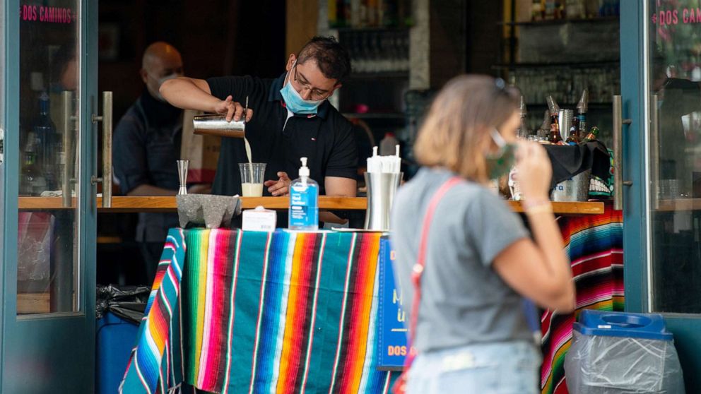 PHOTO: A restaurant employee wearing a mask pours an alcoholic drink into a plastic cup on May 31, 2020 in New York City.