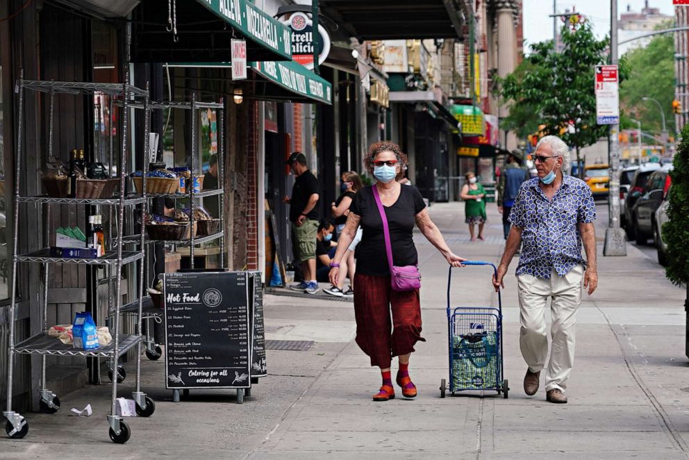 PHOTO: People wearing protective masks walk through Little Italy during the coronavirus pandemic on May 29, 2020 in New York City.