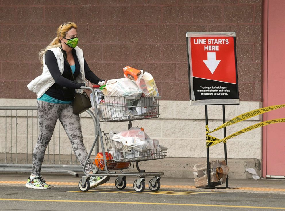 PHOTO: A woman wearing a face mask pushes a cart of groceries past the front of the Giant Supermarket in Spring Township, Pa., April 15, 2020.