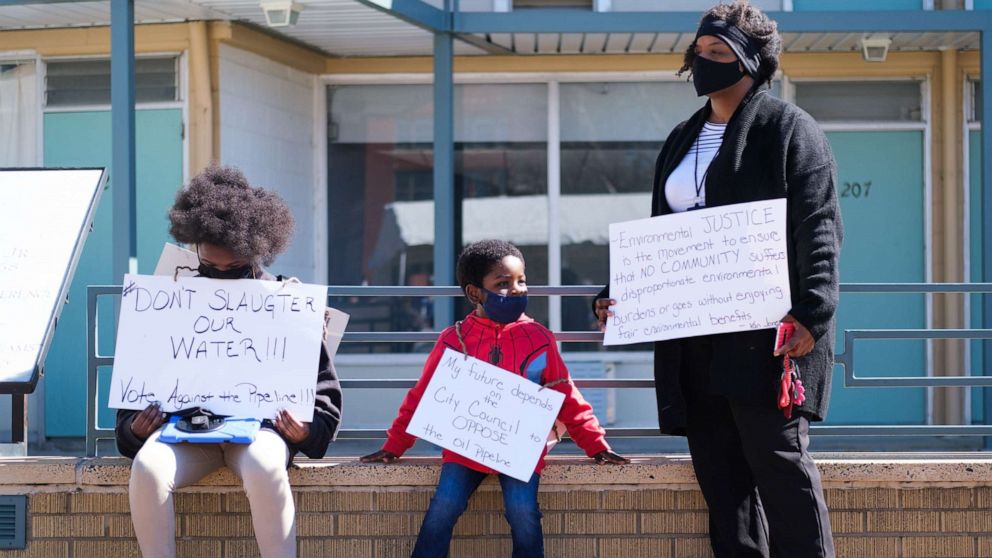 PHOTO: Kizzy Jones, a co-founder of Memphis Community Against the Pipeline, hold signs outside the National Civil Rights Museum with her family during a rally against the construction of the Byhalia Connection Pipeline, Feb. 23, 2021, in Memphis, Tenn.