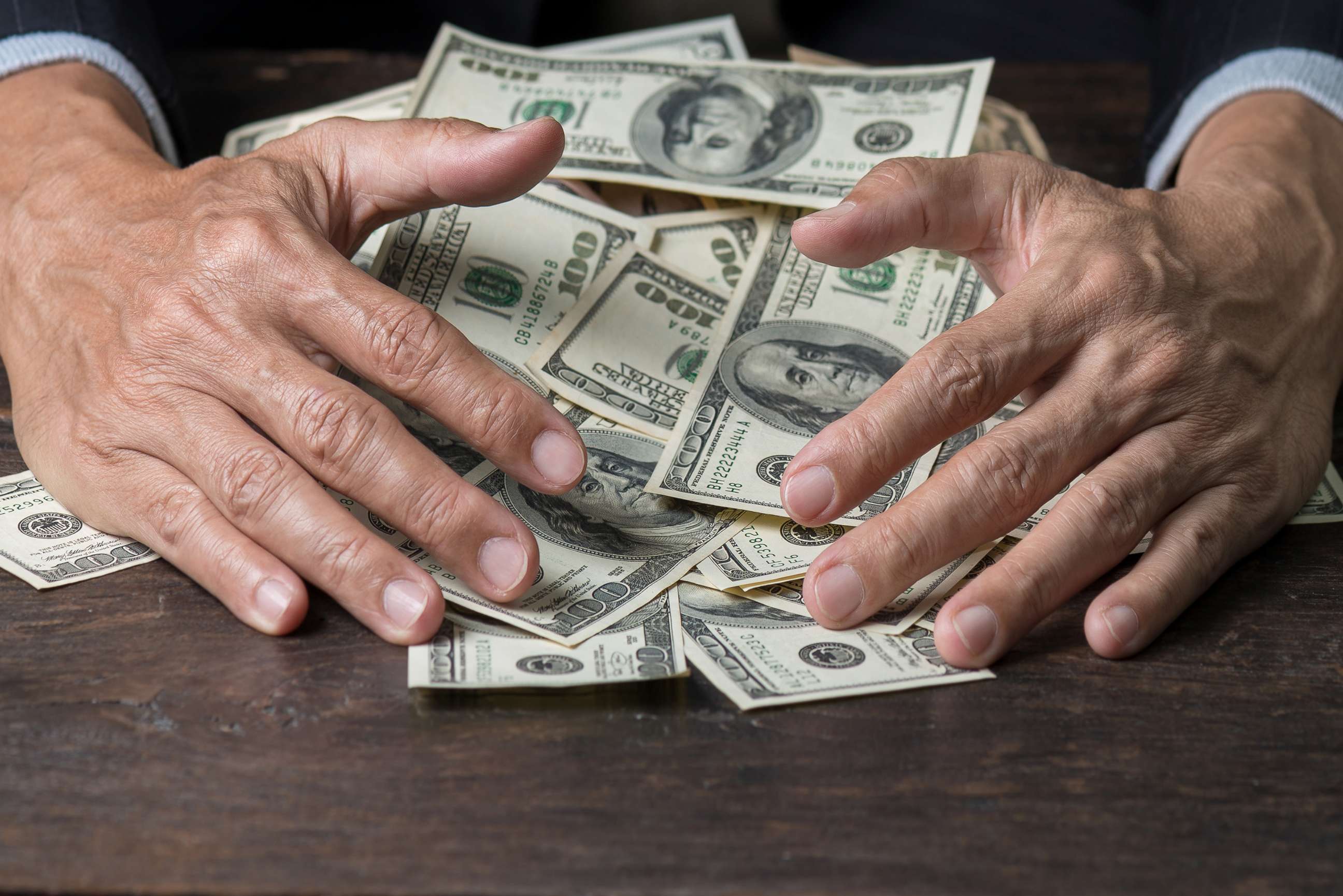 PHOTO: Man's hands sweep money.