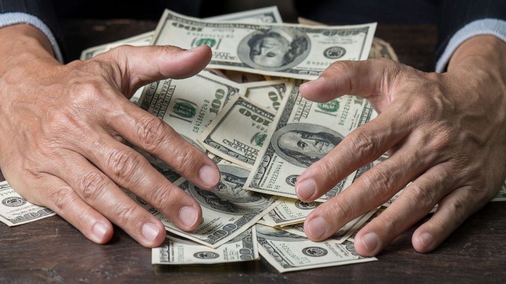 PHOTO: Man's hands sweep money.