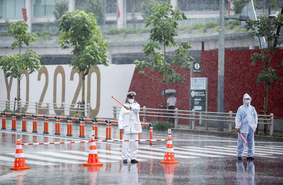 PHOTO: Traffic policemen control the traffic in front of the Olympic stadium in the rain caused by tropical storm Nepartak in Tokyo, July 27, 2021.
