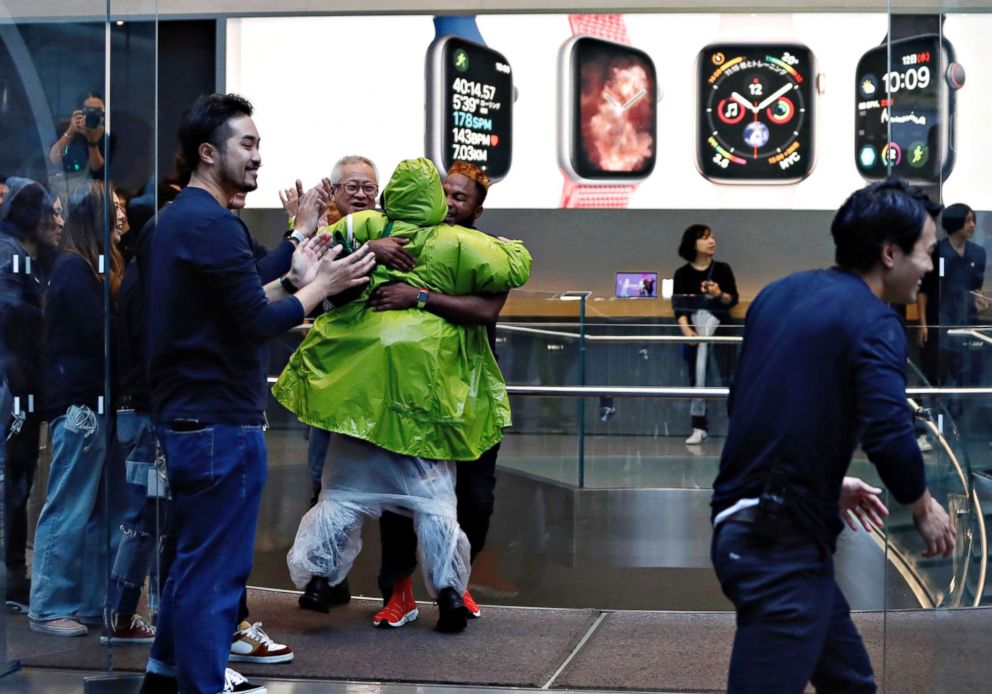 PHOTO: Apple Store staff person greets customers who have been waiting in line to purchase Apple's new iPhone XS and XS Max in Tokyo's Omotesando shopping district, Sept. 21, 2018. 