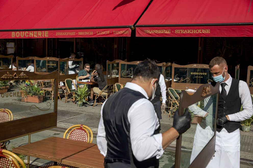 PHOTO: Waiters at a restaurant adjust social distancing screens outside for outdoor seating seating that follows current health guidelines to slow the spread of Coronavirus (COVID-19) at a restaurant in New York, June 25, 2020.