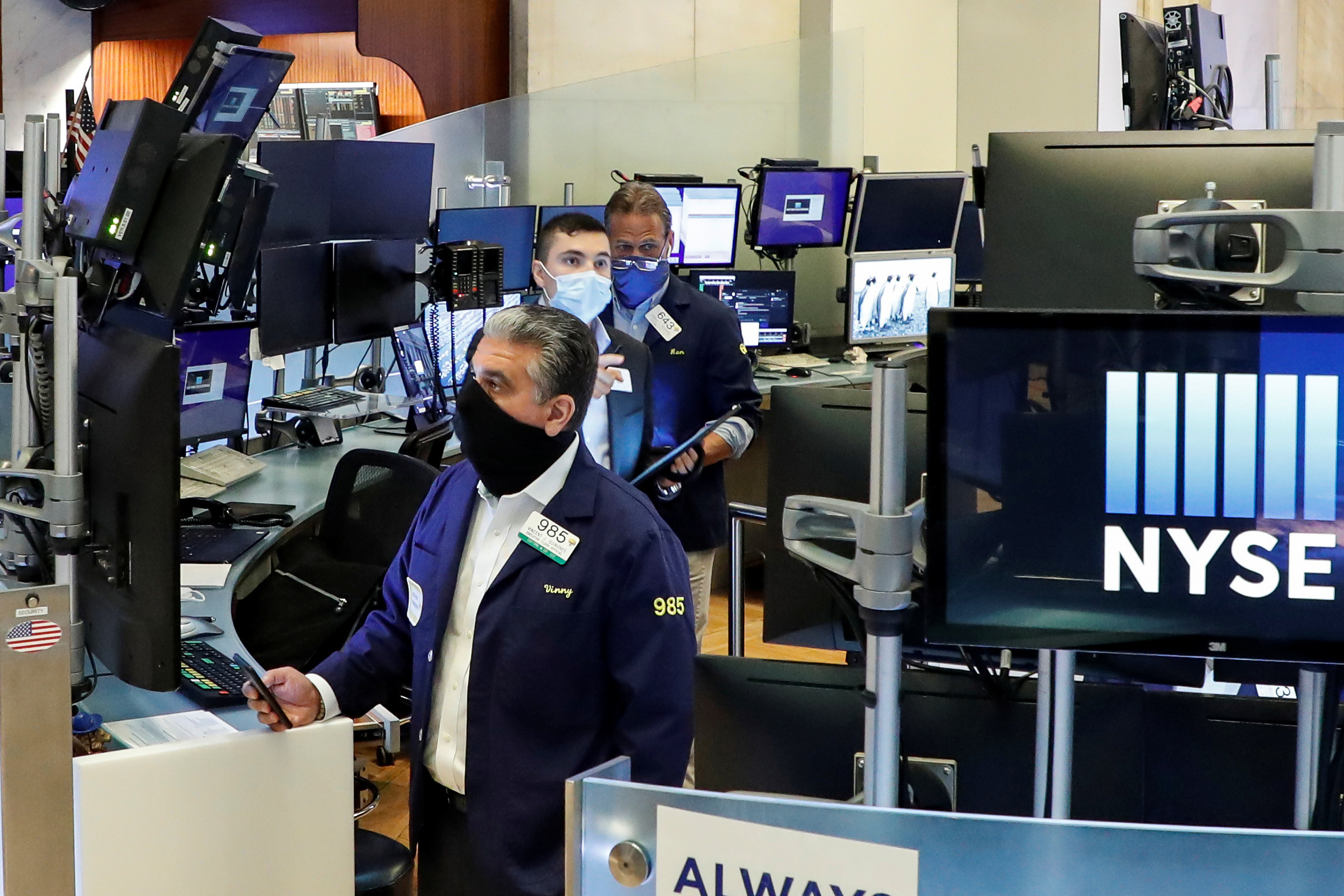 PHOTO: Traders wearing masks work, on the first day of in-person trading since the closure during the outbreak of the coronavirus (COVID-19) on the floor at the New York Stock Exchange (NYSE) in New York City, May 26, 2020.