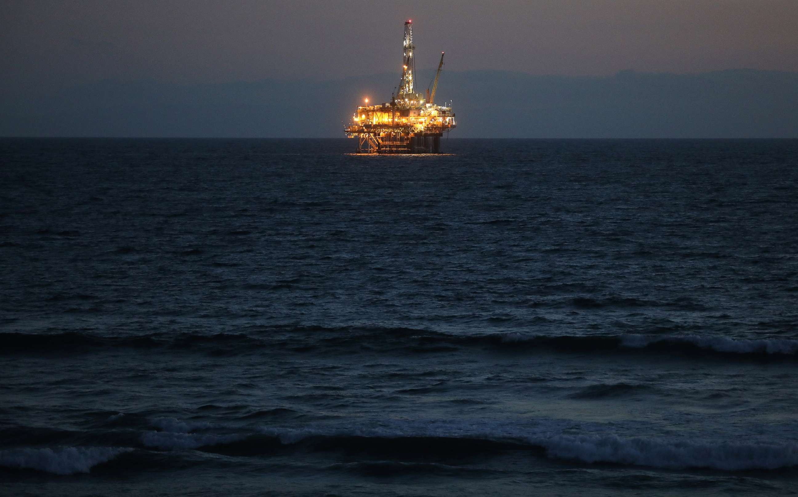 PHOTO: An offshore oil platform glows at dusk off the coast of Huntington Beach, Calif., April 20, 2020.